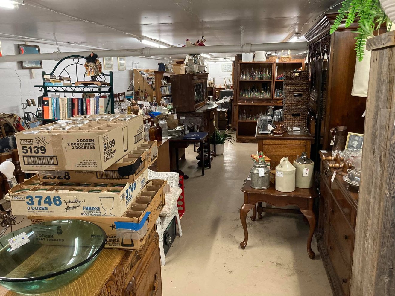 One corner of the shop's floor — bookcases, cabinets, crocks and stacked crates of glassware under a low ceiling